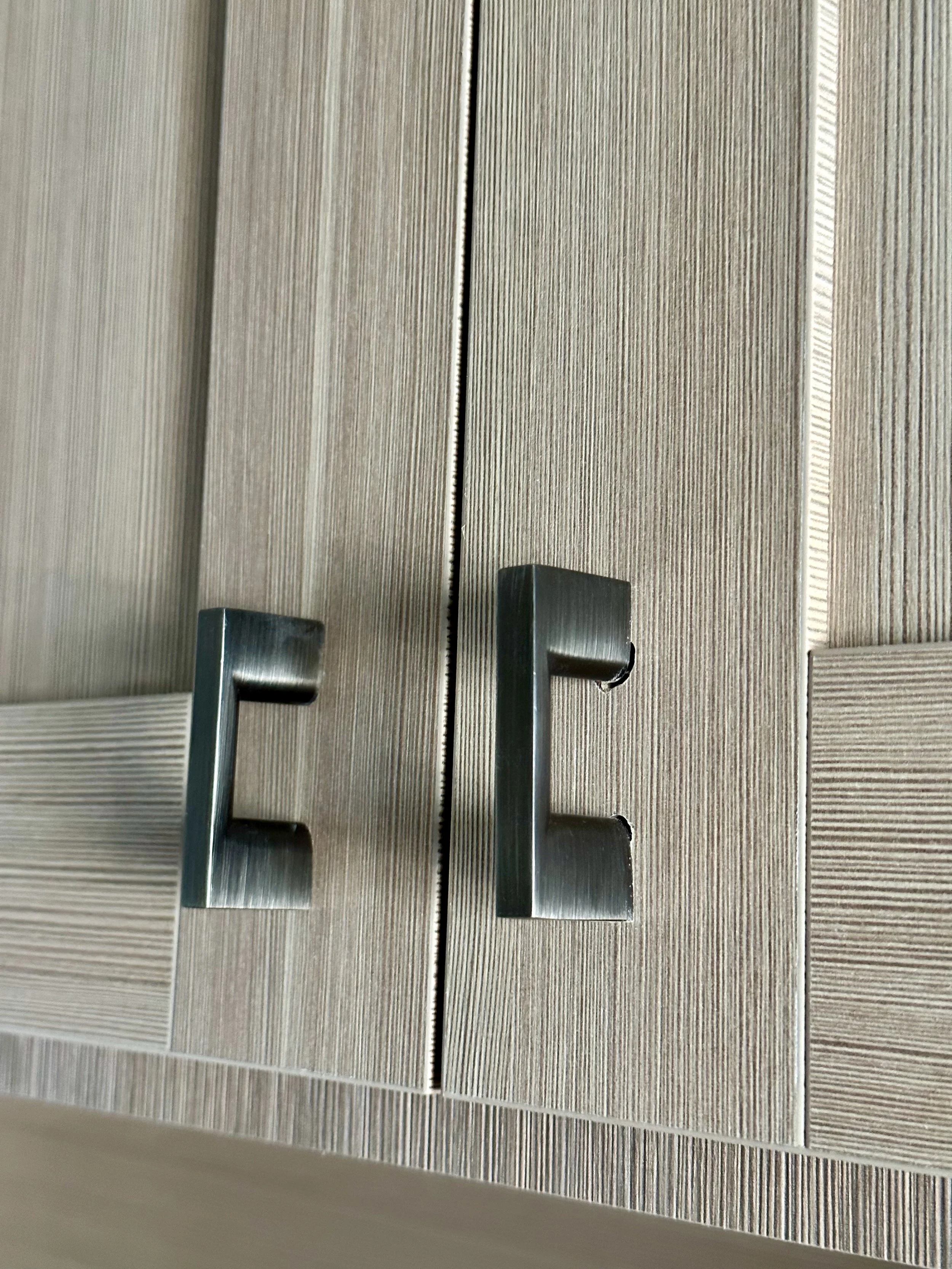 Close-up of two wooden cabinet doors with silver handles and textured surface.