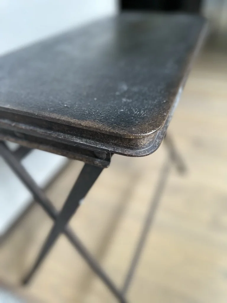 Close-up of a wooden folding table with metal legs.