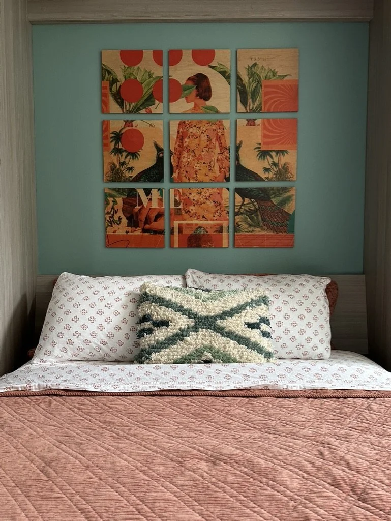 Bedroom with decorative art above bed, featuring grid of nine abstract panels with nature and human figure design; bed with patterned pillows and textured throw blanket.