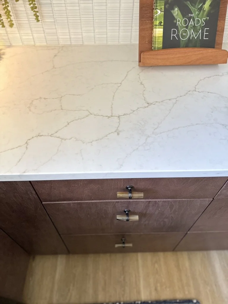 Marble countertop with drawer handles and a book titled 'The Roads to Rome' on a wooden stand.