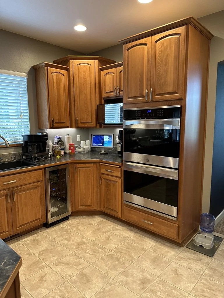 Modern kitchen with wooden cabinets, double wall oven, coffee maker, wine cooler, and water dispenser.