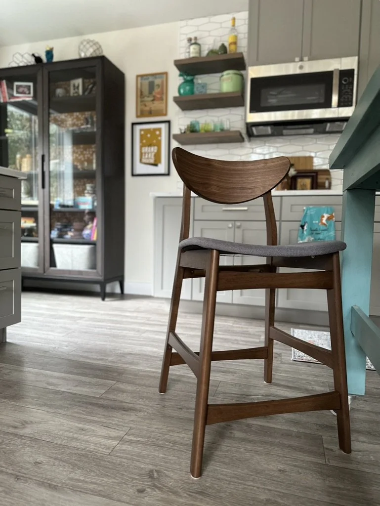 Kitchen interior with a wooden chair, gray cabinets, a glass cabinet, hanging shelves with decor, and a microwave.
