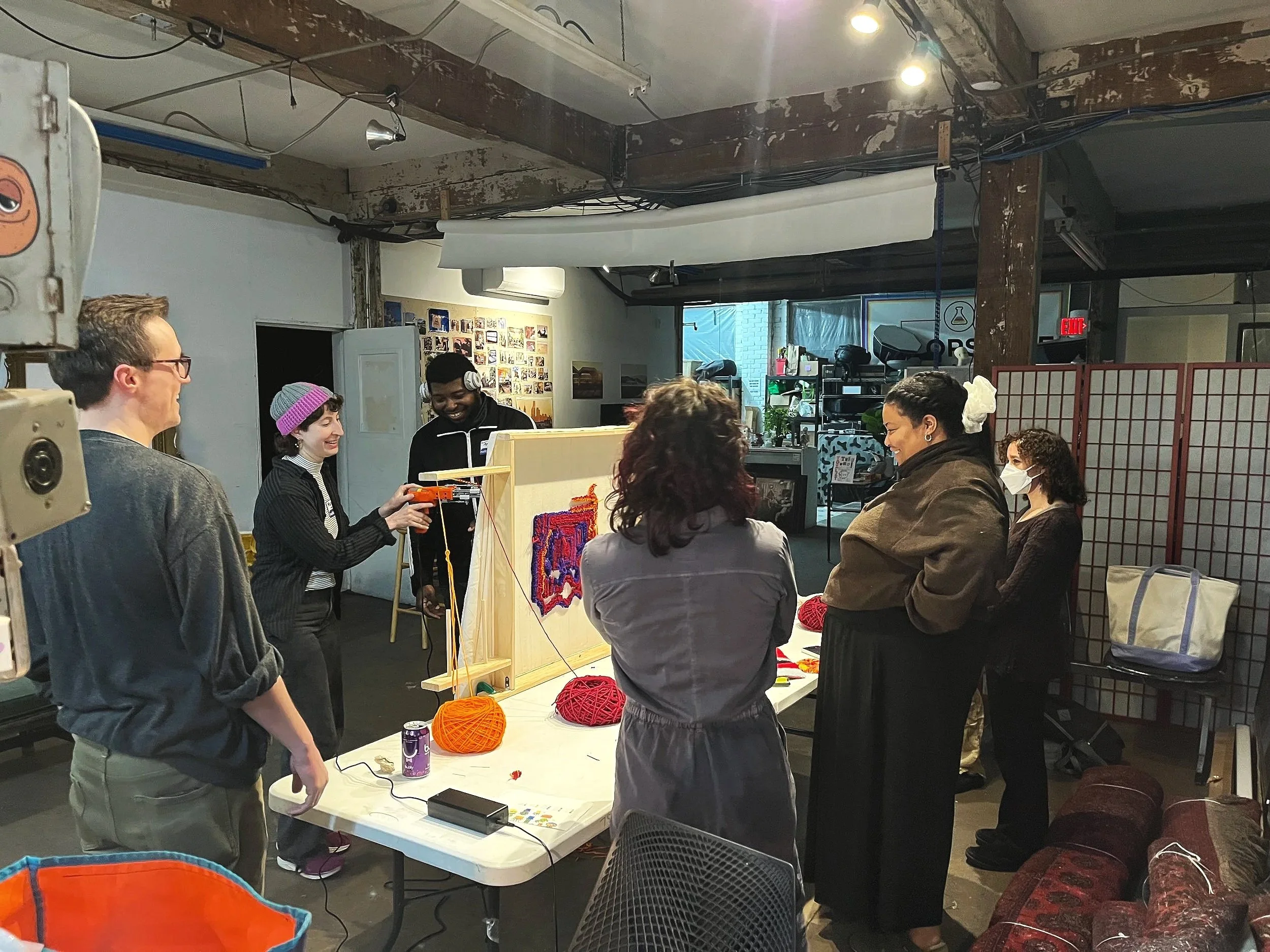 A diverse group of adults trying out a tufting gun during a demo.