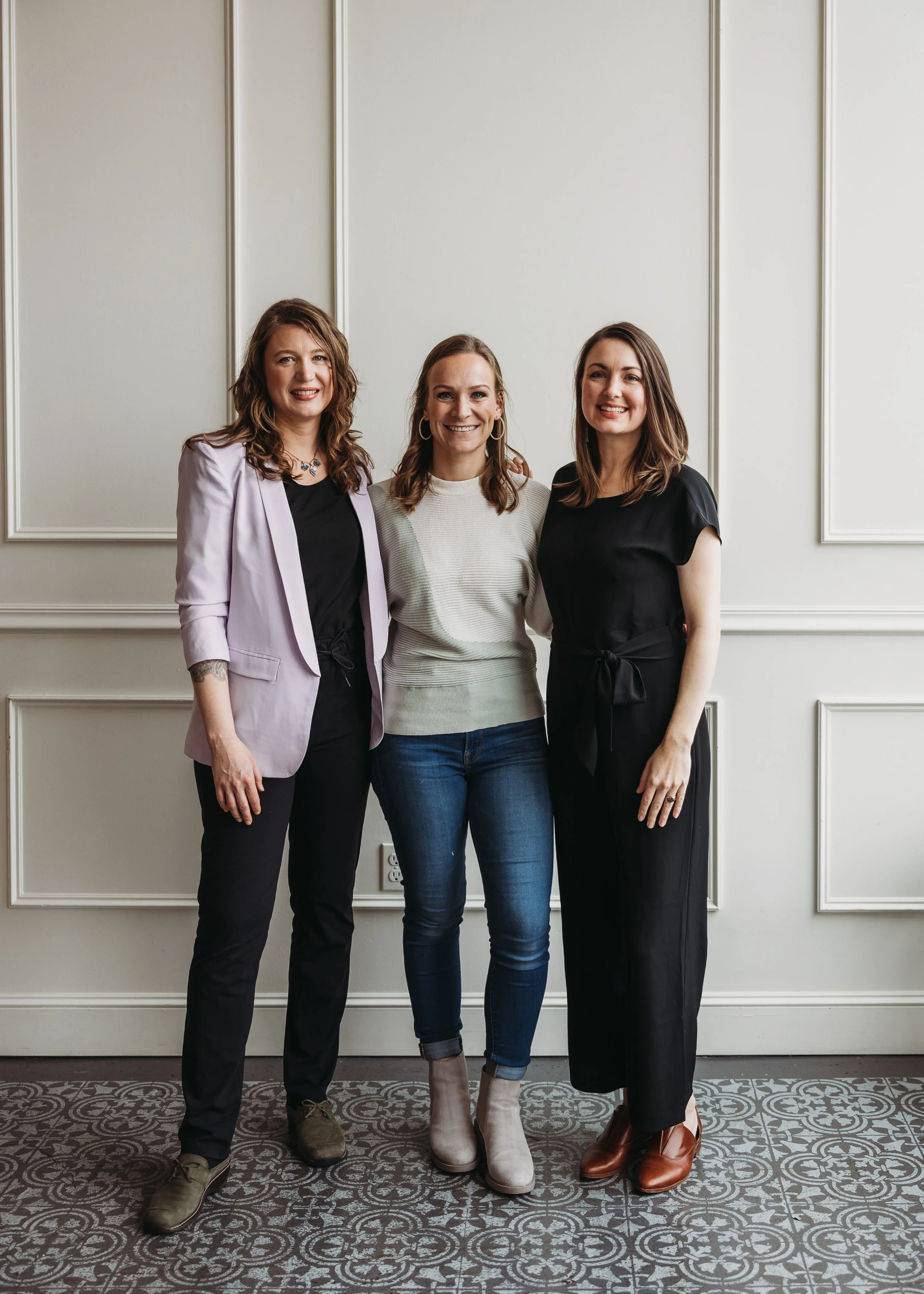 Three women standing together smiling, representing supportive team for online birth classes and expectant parents