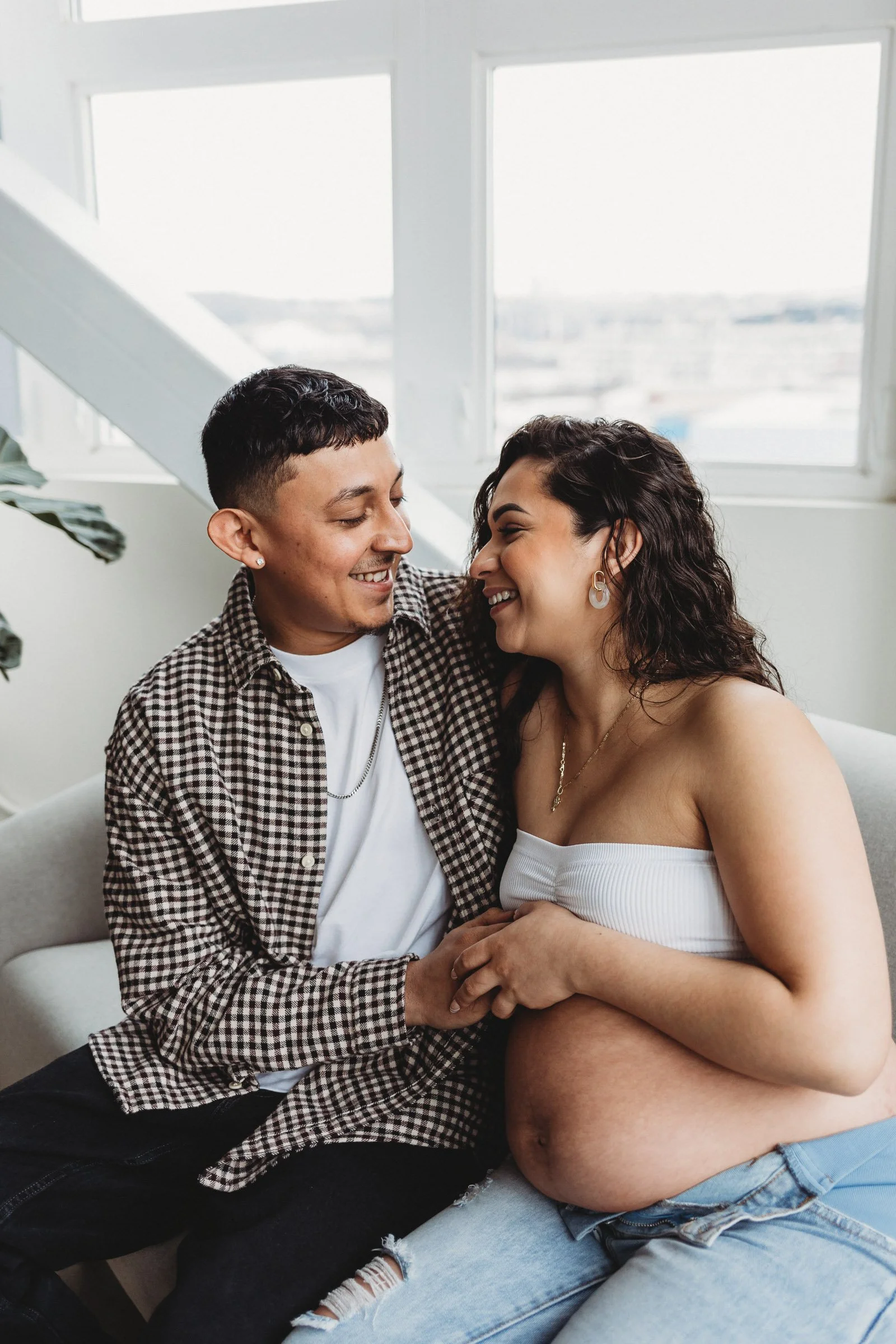 Pregnant couple smiling and holding belly together, showing love and connection as expectant parents