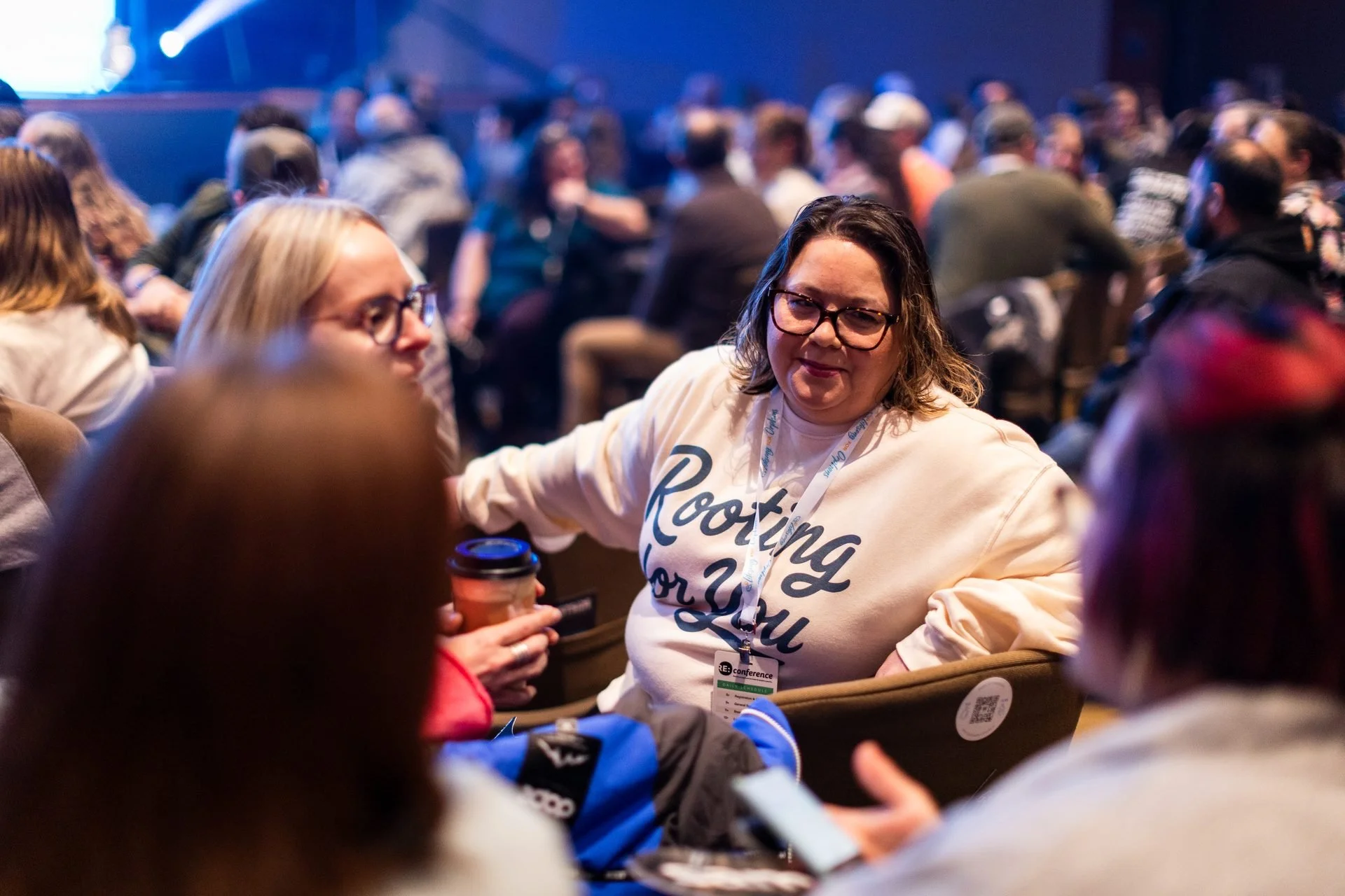 RE: Conference gallery: smiling attendee in a branded sweatshirt in the conference crowd
