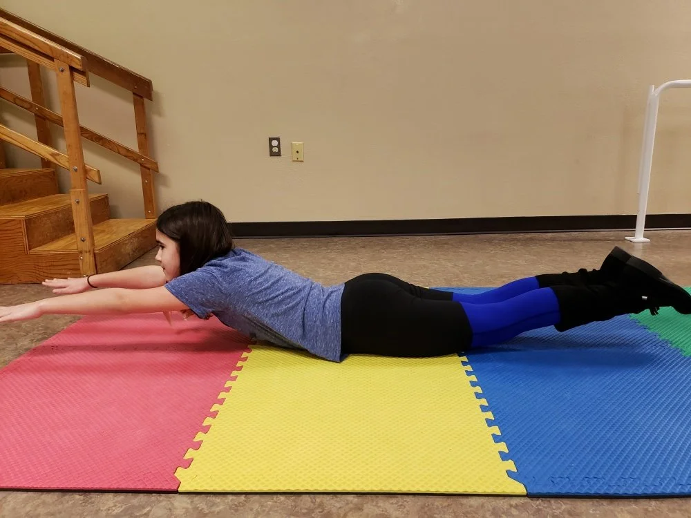 Lying on the floor with your arms straight overhead and legs extended, reaching up and lift all limbs off the floor. Tighten your core and your butt muscles. Hold this position. If there is pain, stop the exercise. Hold position for 10seconds, complete 5 sets. Repeat 2x/day. Take breaks as needed.