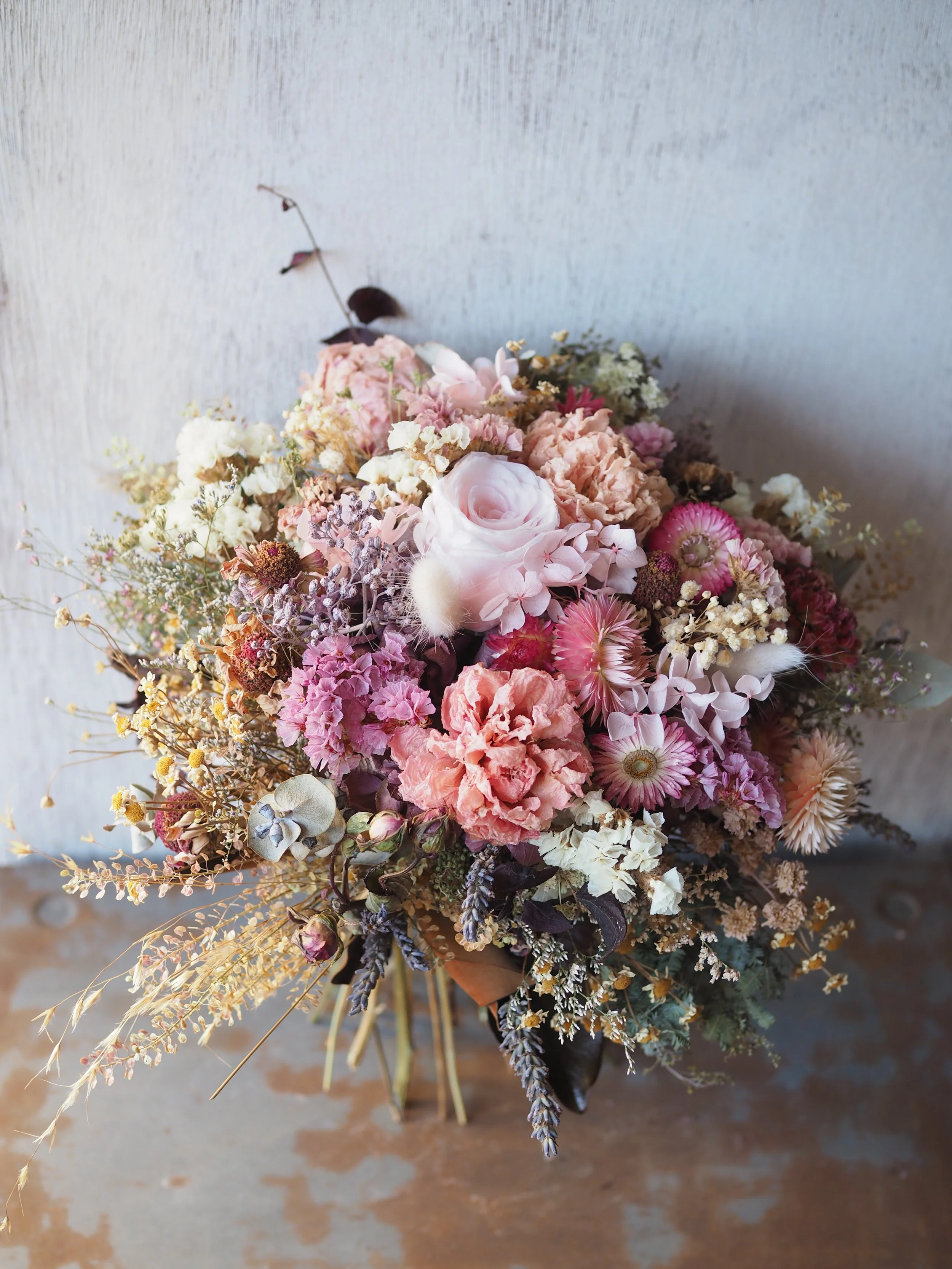The Pretty in Pink Posy is a delicate and charming dried and preserved floral arrangement in tonal pinks, peach, creams, and antique tones.