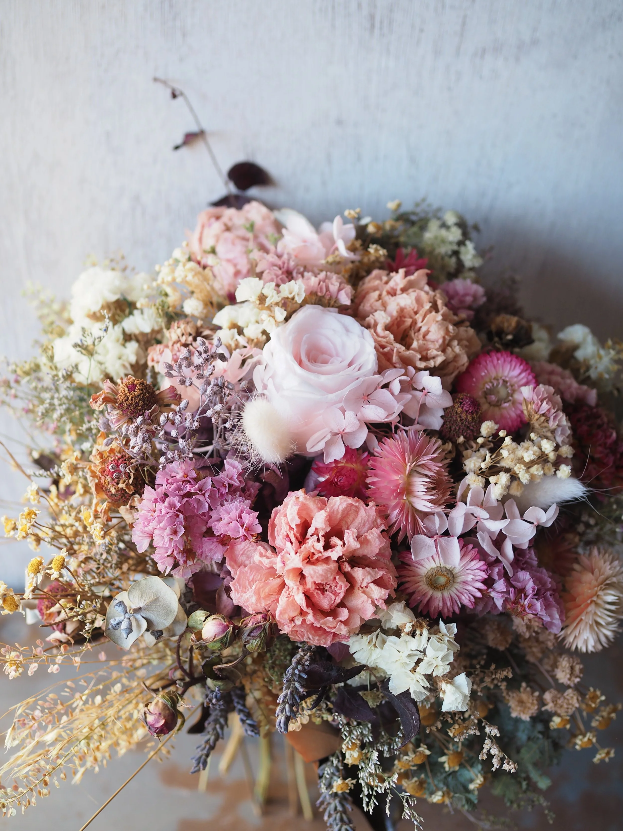 The Pretty in Pink Posy is a delicate and charming dried and preserved floral arrangement in tonal pinks, peach, creams, and antique tones.