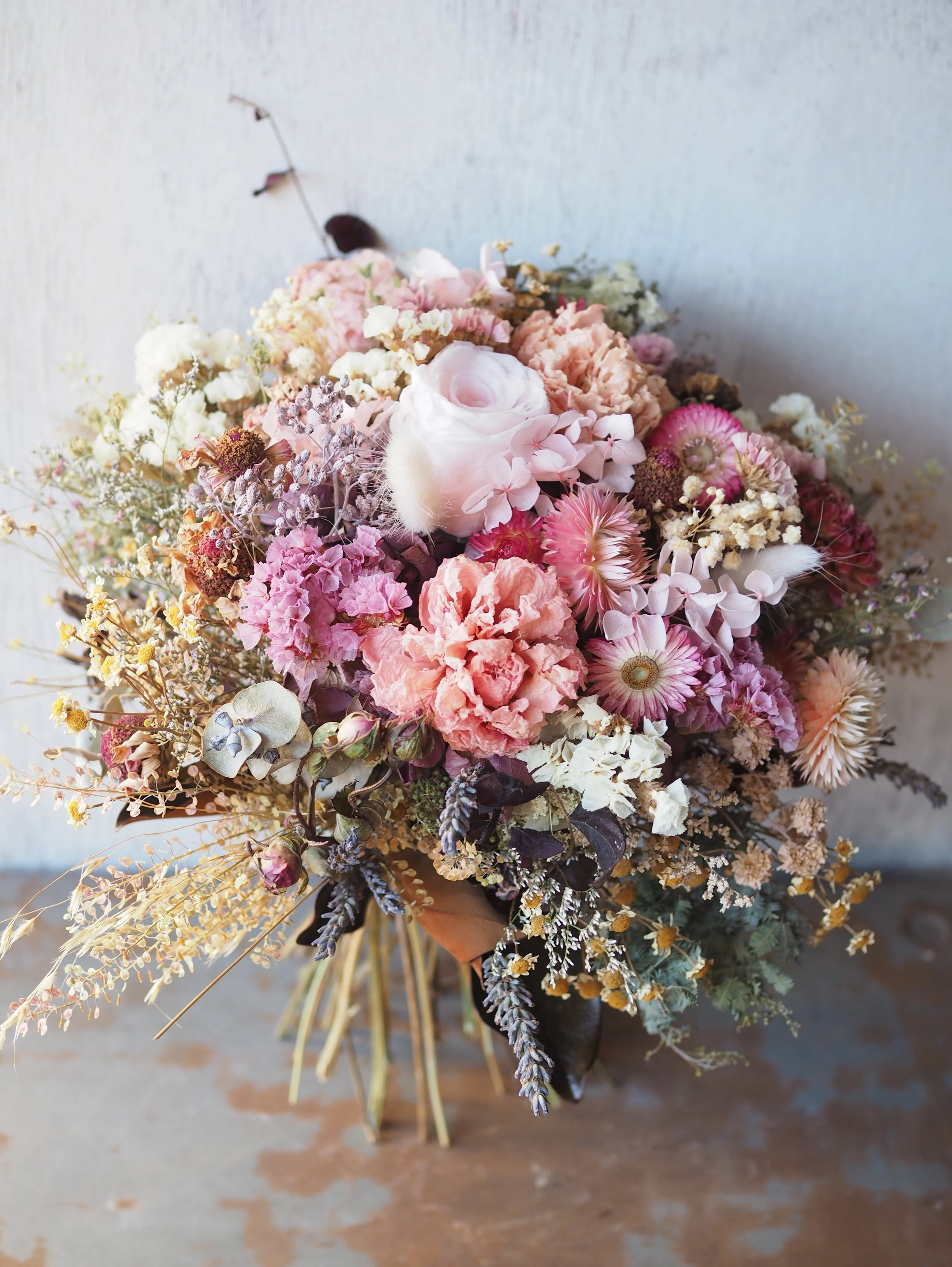 The Pretty in Pink Posy is a delicate and charming dried and preserved floral arrangement in tonal pinks, peach, creams, and antique tones.