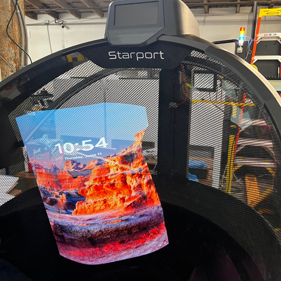 A close up of the Starport Explorer canopy showing a bright digital landscape of red rock formations rendered on a transparent screen within the dome structure.