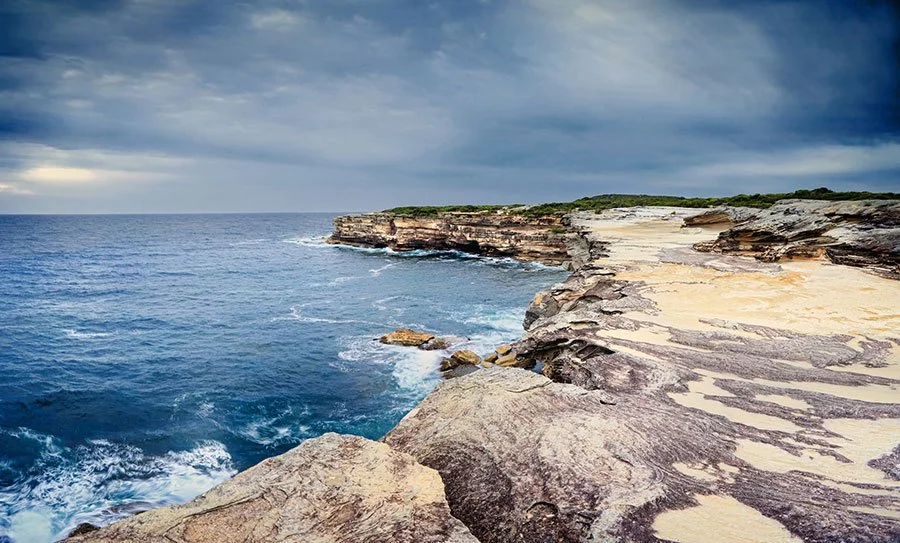 Wind-carved sandstone cliffs and ocean views along a dramatic coastal walking trail near Sydney