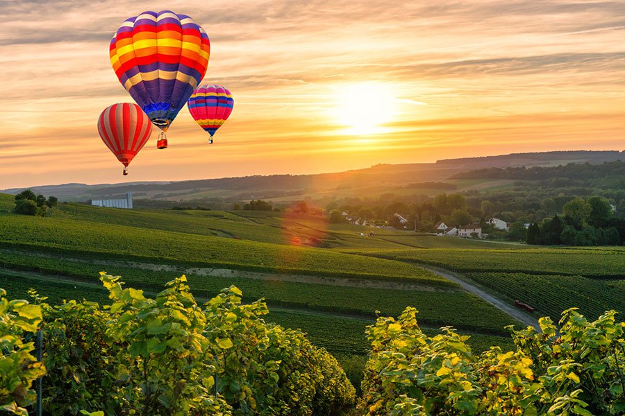 Hot air balloons floating over vineyard rows at sunrise during a wine country weekend getaway