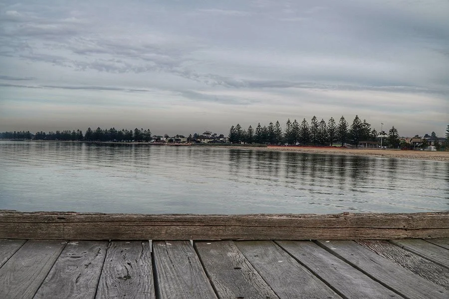 View of Altona’s coastal bike trail in Melbourne with calm water and reflections, a scenic route for relaxed cycling