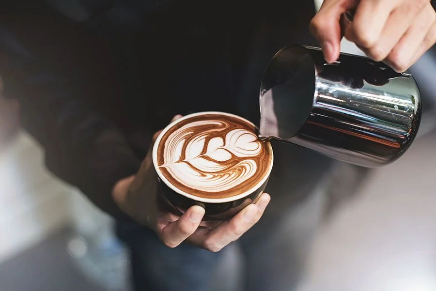 Close-up of barista pouring latte art into a coffee cup, perfect for a Father’s Day workshop experience in Sydney