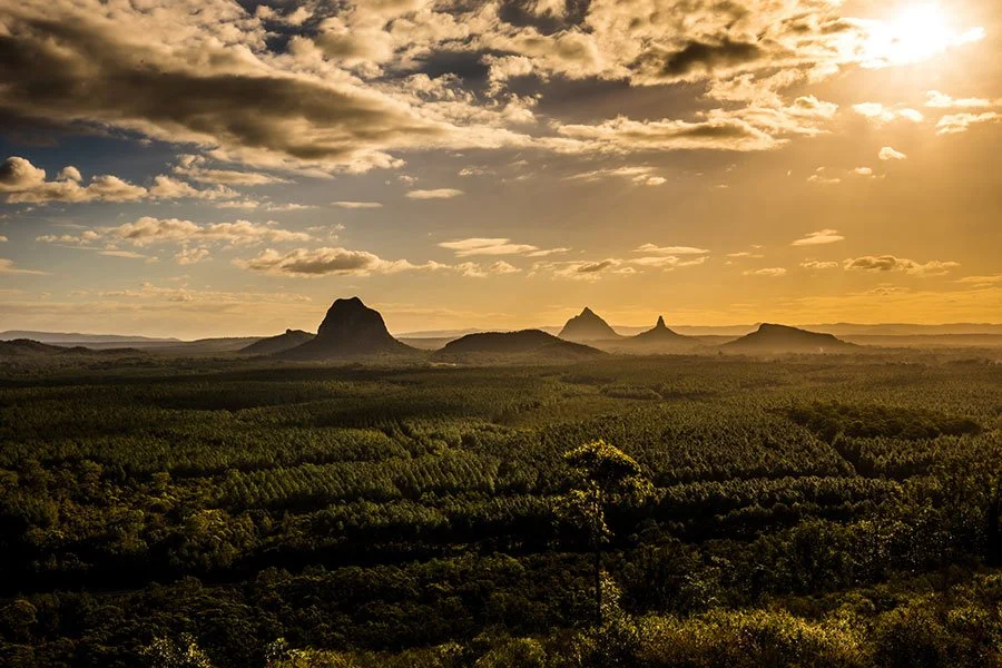 Sunset view over the Glass House Mountains in Queensland, showcasing dramatic peaks and popular hiking trails near Brisbane.
