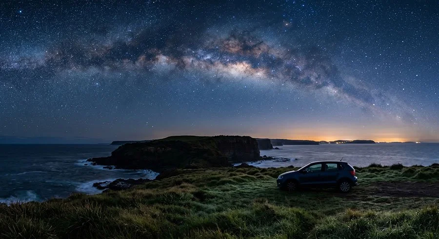 Milky Way arching over a dark coastal headland with car parked nearby, stargazing scene in NSW