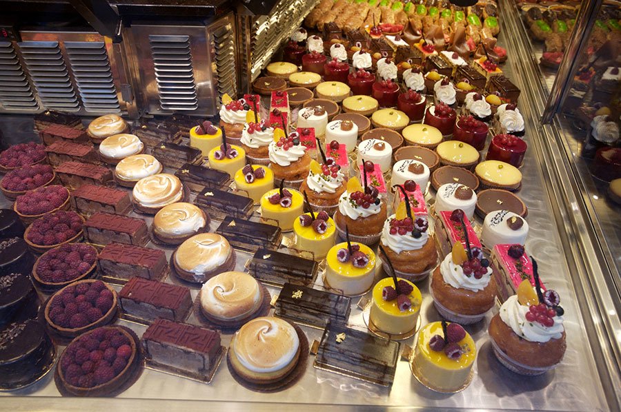 Assorted cakes and pastries in a bakery display, including red velvet, custard tarts, cheesecakes, and doughnuts — perfect for fans of bold, nostalgic sweets in Melbourne.