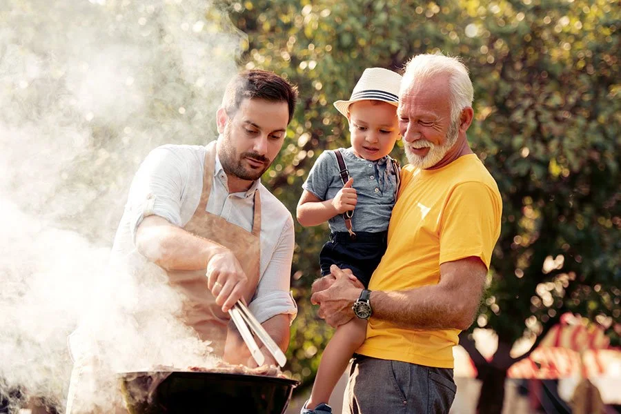 Family cooking on a barbecue outdoors, capturing a relaxed Father’s Day picnic and bonding time in Melbourne’s parks