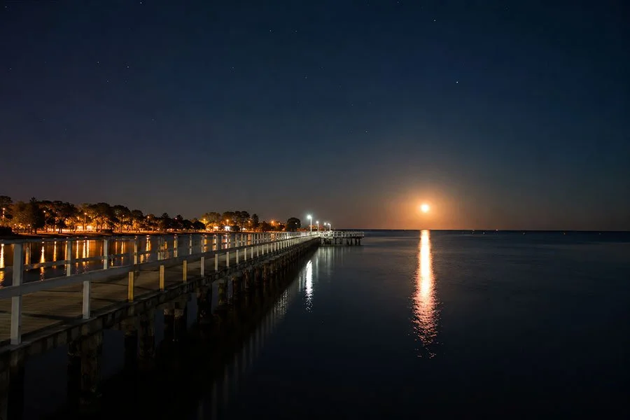 Redcliffe Jetty extending into Moreton Bay at night with full moon reflected on calm water