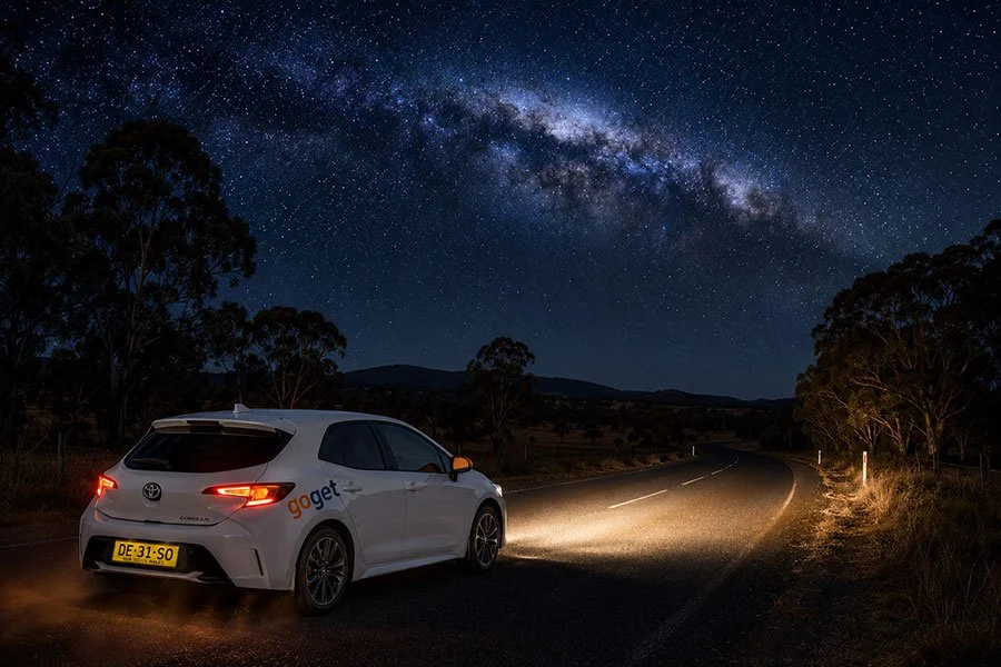 GoGet carshare car driving along a dark Queensland hinterland road at night with a star-filled sky overhead