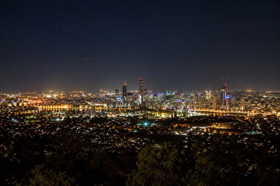 Brisbane city lights from Mount Coot-tha Lookout at night, soft glow across the skyline with dark sky above