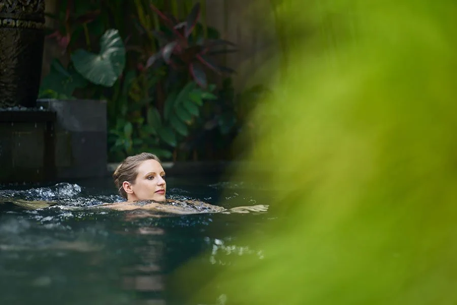 Woman relaxing in outdoor luxury spa pool surrounded by tropical greenery at wine country resort