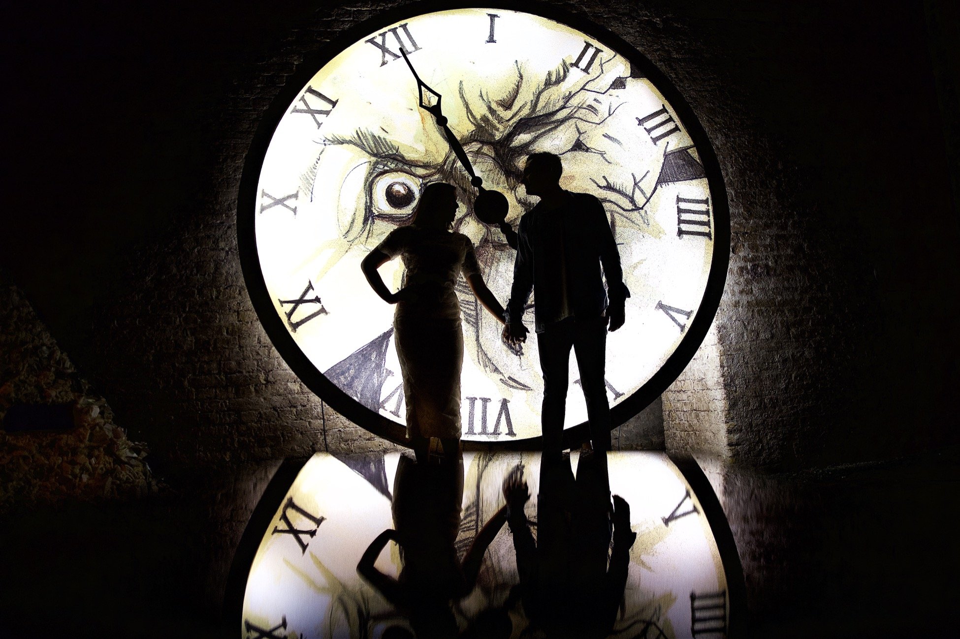 Silhouettes of a man and woman holding hands in front of a large clock face with Roman numerals, featuring a jagged eye illustration in the background.