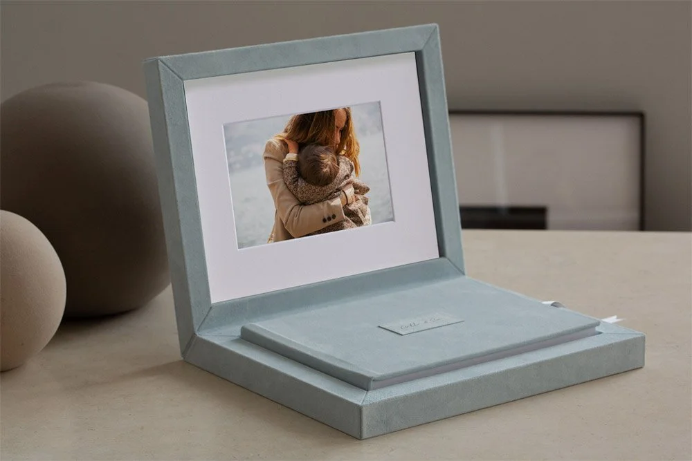 Open jewelry box with a framed photo of a woman holding a small child inside.