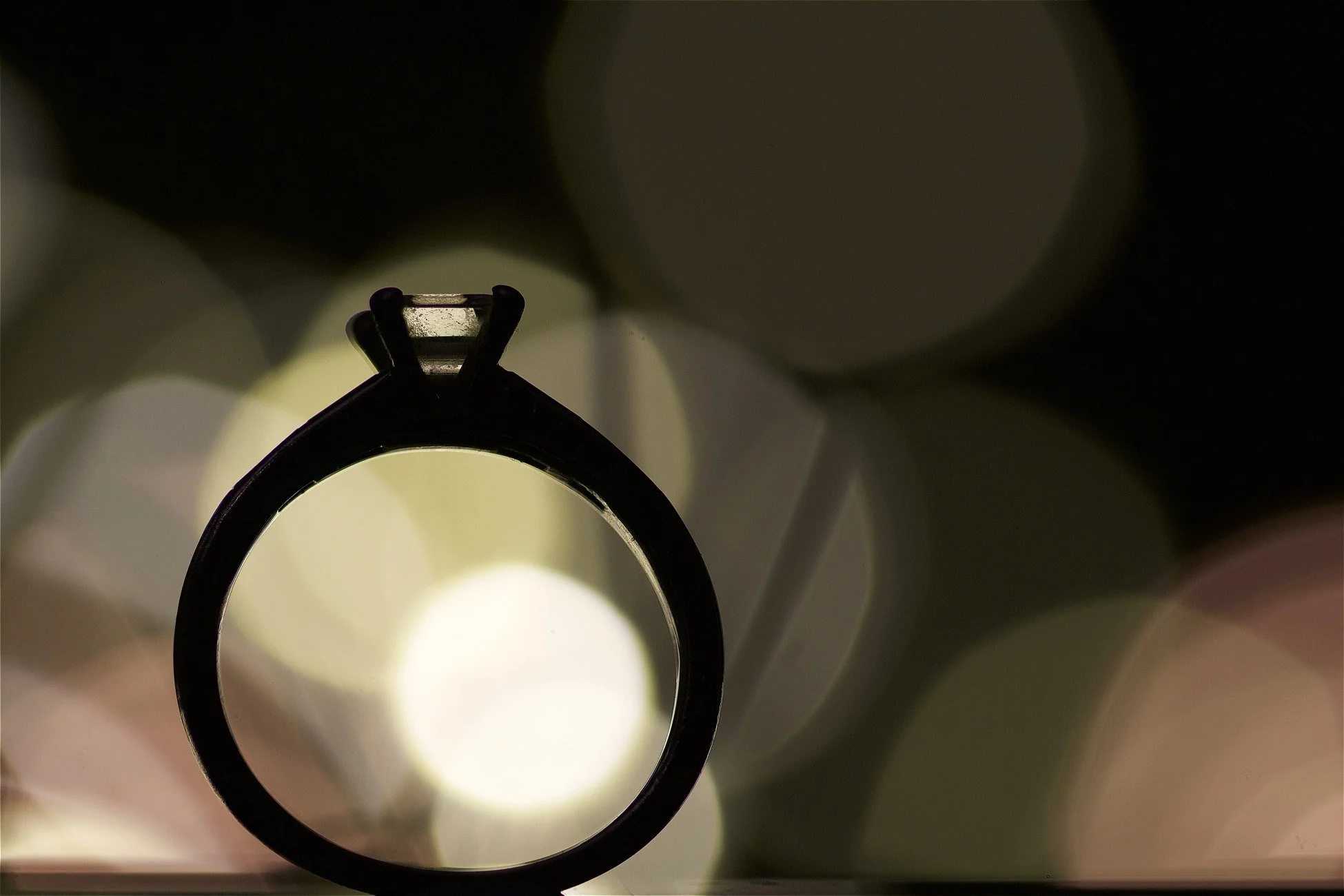 Close-up view of a ring from a top-down perspective, with blurred circular light reflections in the background.