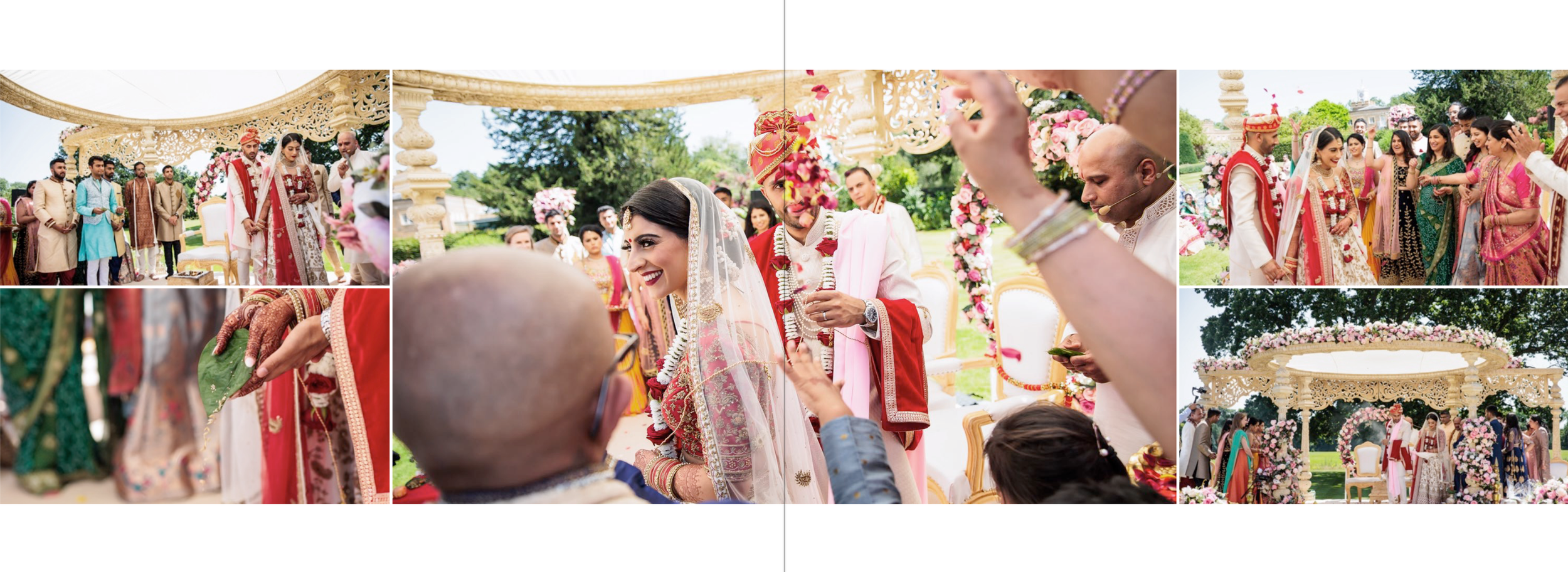 A traditional Indian wedding ceremony outdoors with the bride and groom dressed in red and pink, surrounded by family and friends, under a floral decorated arch.
