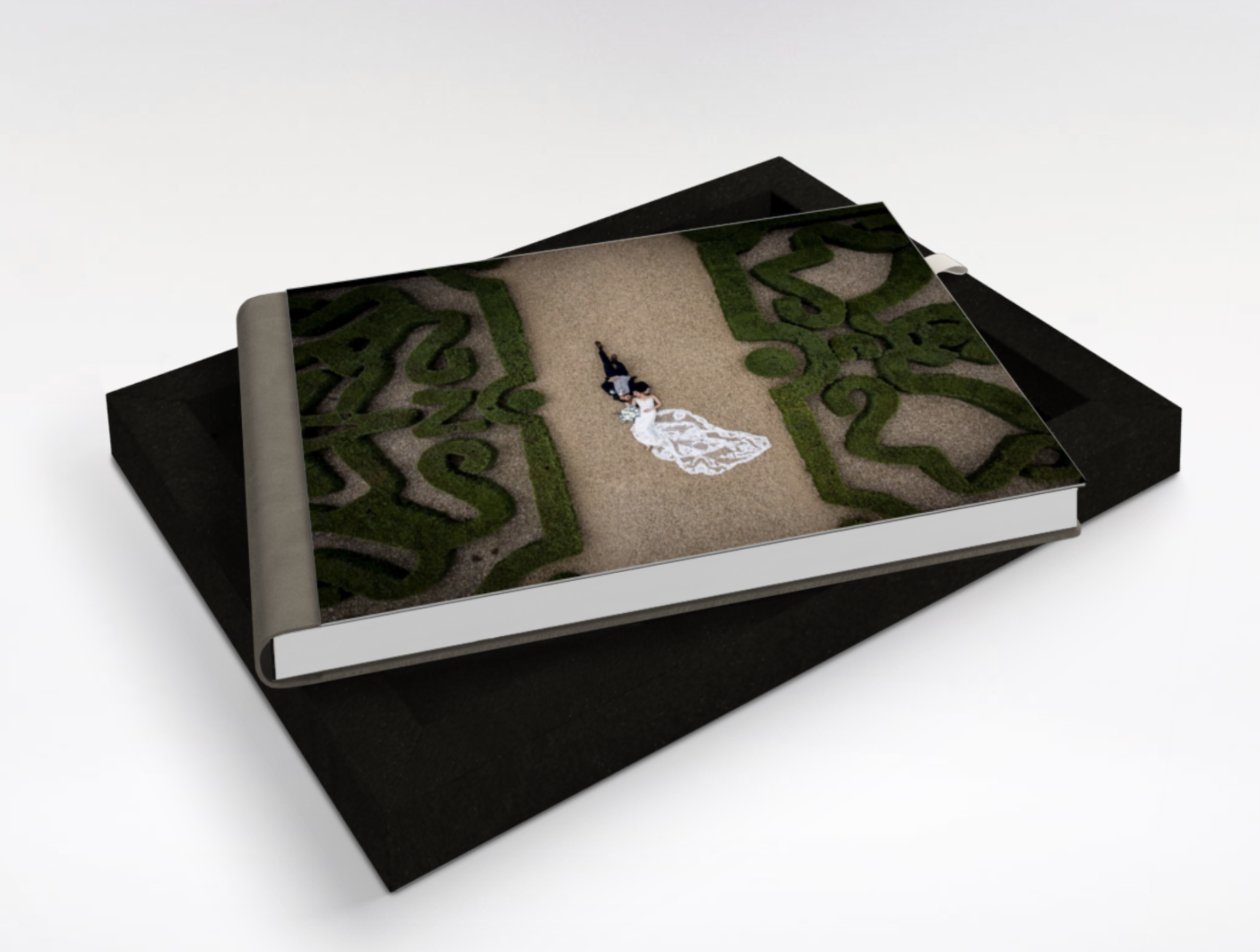A framed artwork of a bride and groom lying on a path surrounded by green hedge designs.