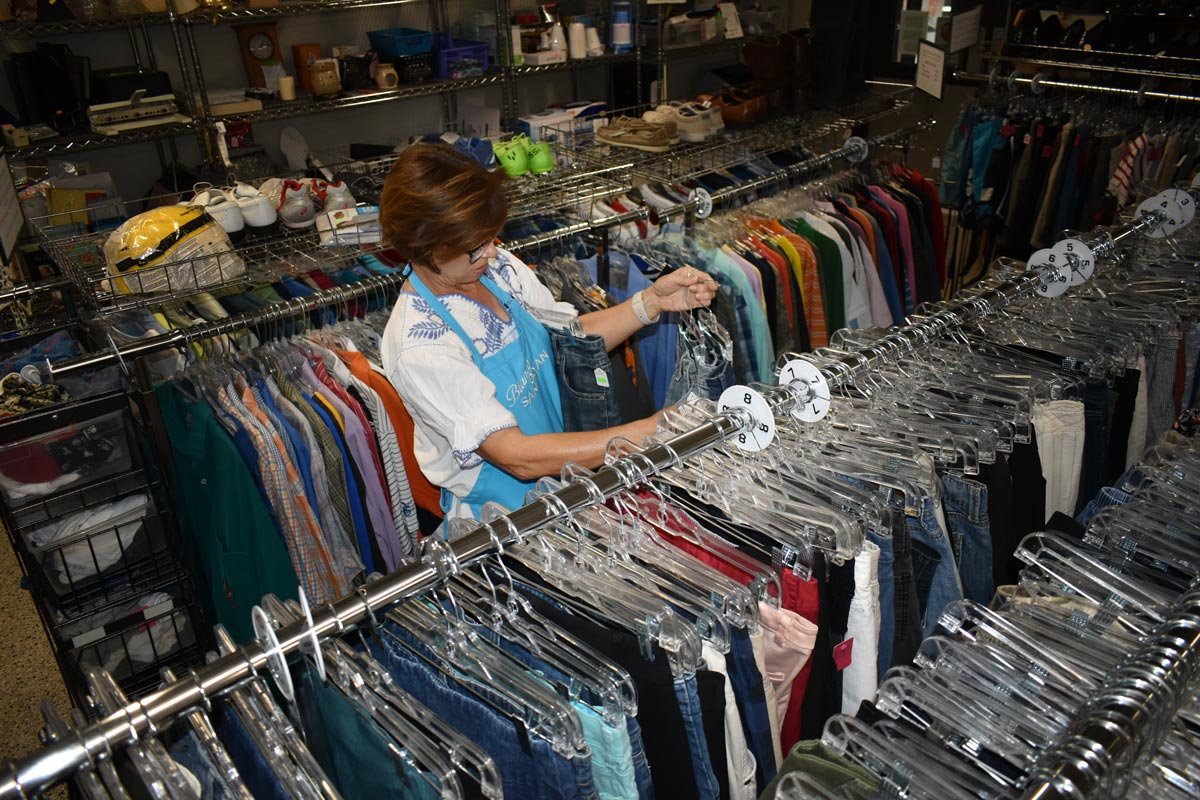 female volunteer stocking hangers with clothing at the Good Samaritan thrift store and food pantry in Blanco, Texas