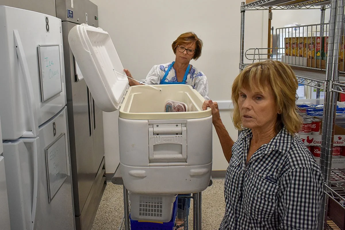 two female volunteers getting food out of a cooler at the Good Samaritan thrift store and food pantry in Blanco, Texas