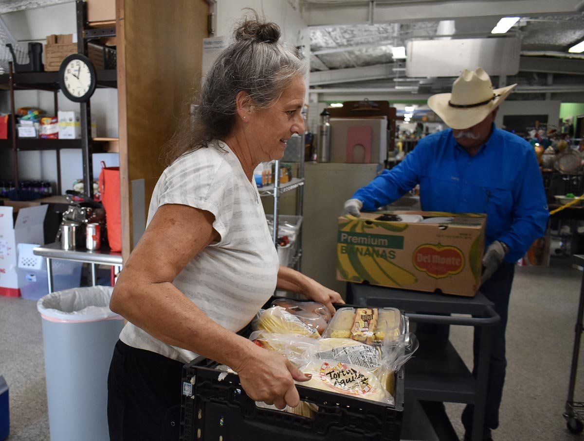 female volunteer carrying a box with food  at the Good Samaritan thrift store and food pantry in Blanco, Texas