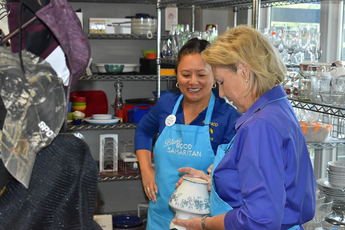 two female volunteers working on a shelf with merchandise at the Good Samaritan thrift store and food pantry in Blanco, Texas