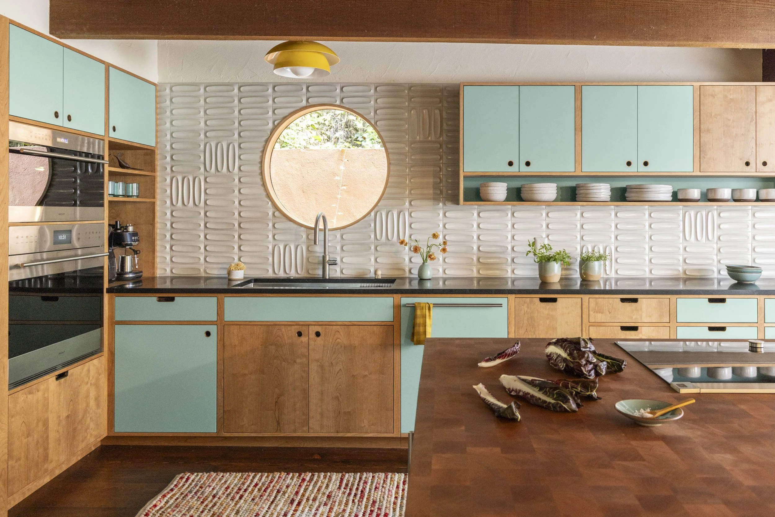 Modern kitchen design, blue cabinet, light wood, white tile, yellow lamp.