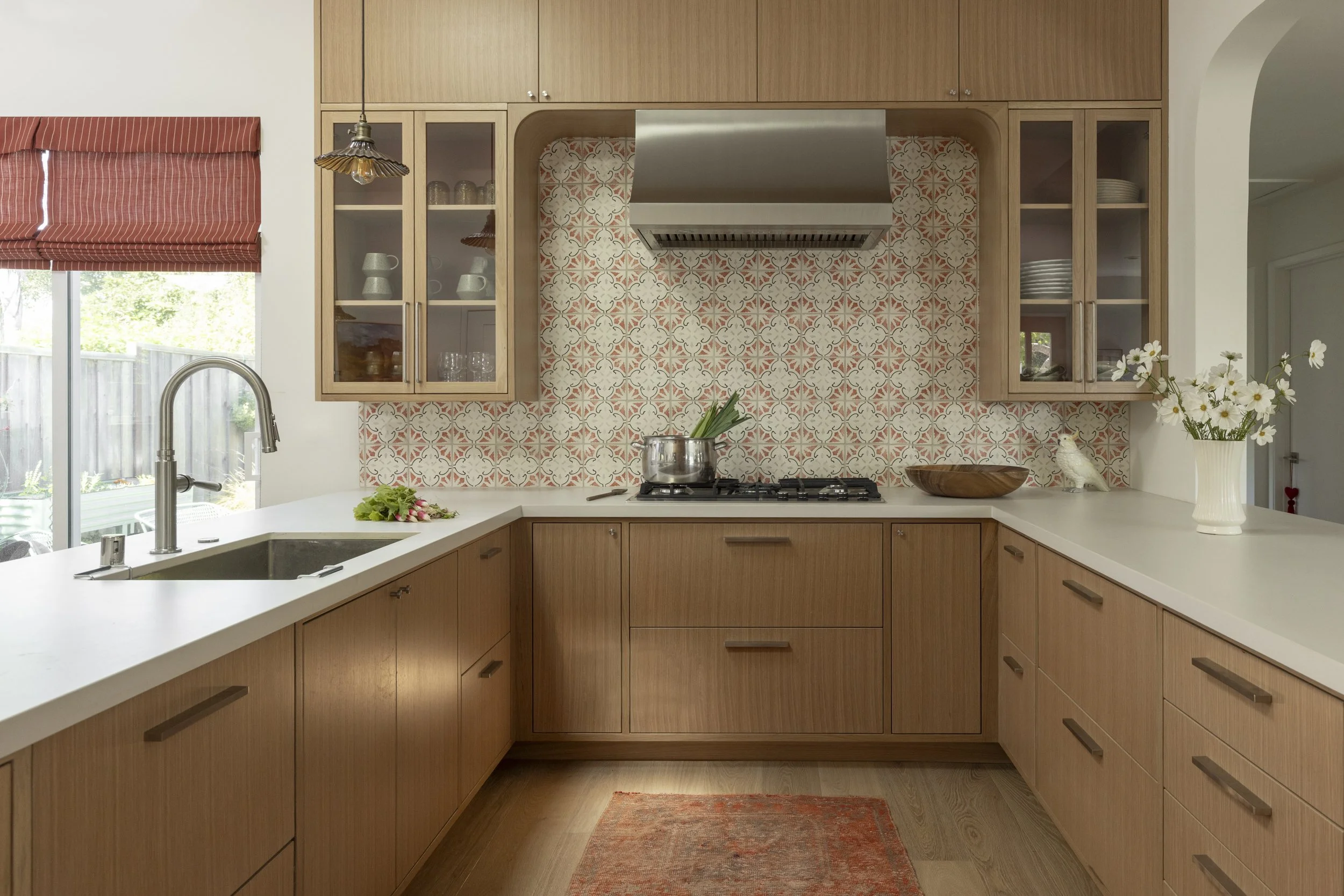 Kitchen design with warm wood, tile, glass cabinet, red accents.