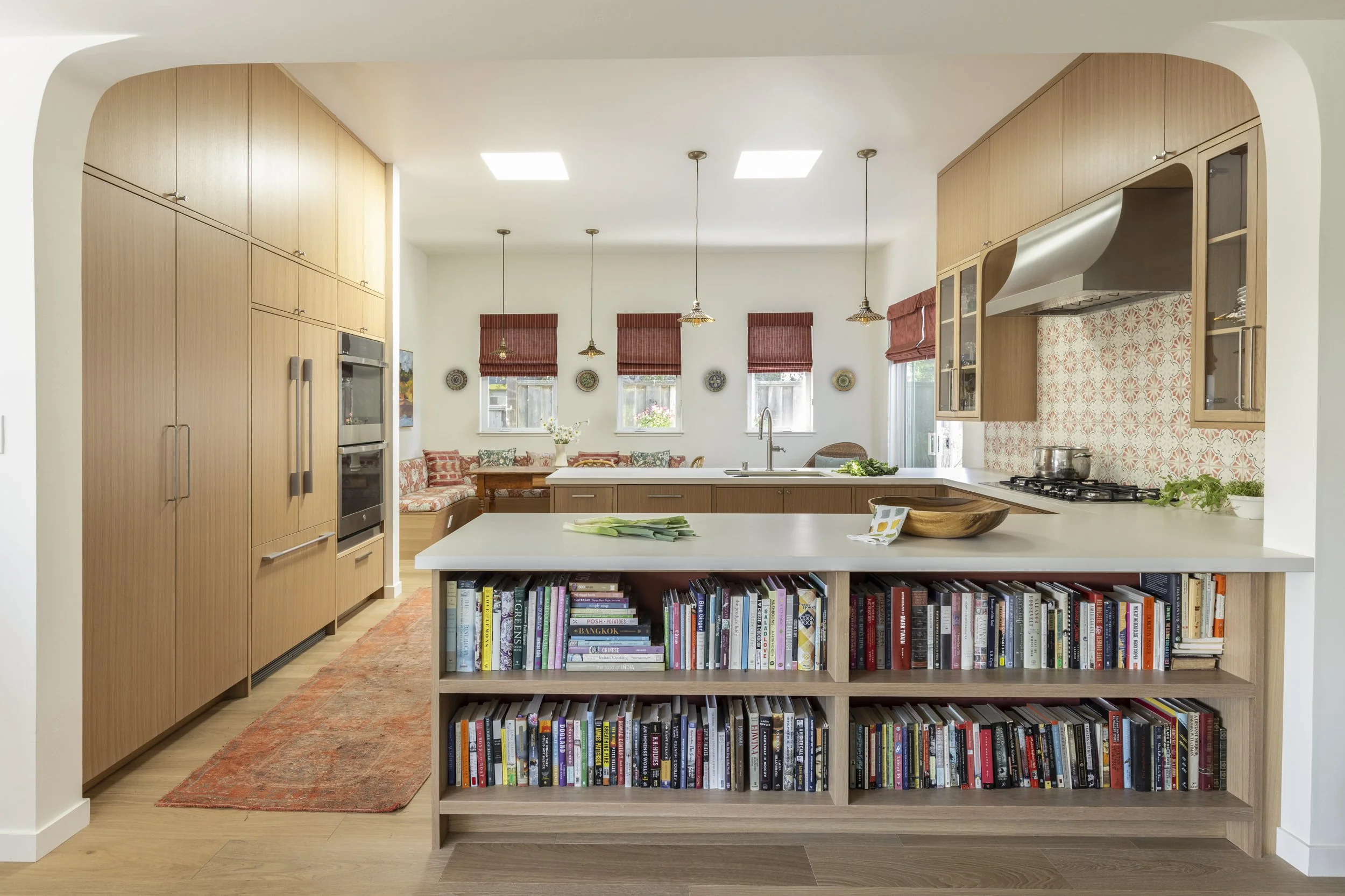 Kitchen design with warm wood, glass door cabinets, red accents.
