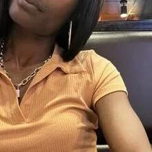 A woman wearing a yellow polo shirt with a gold chain necklace