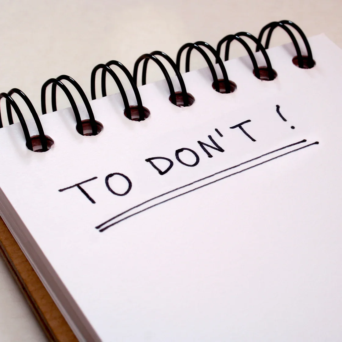 lined spiral wound notebook with to don't written on it