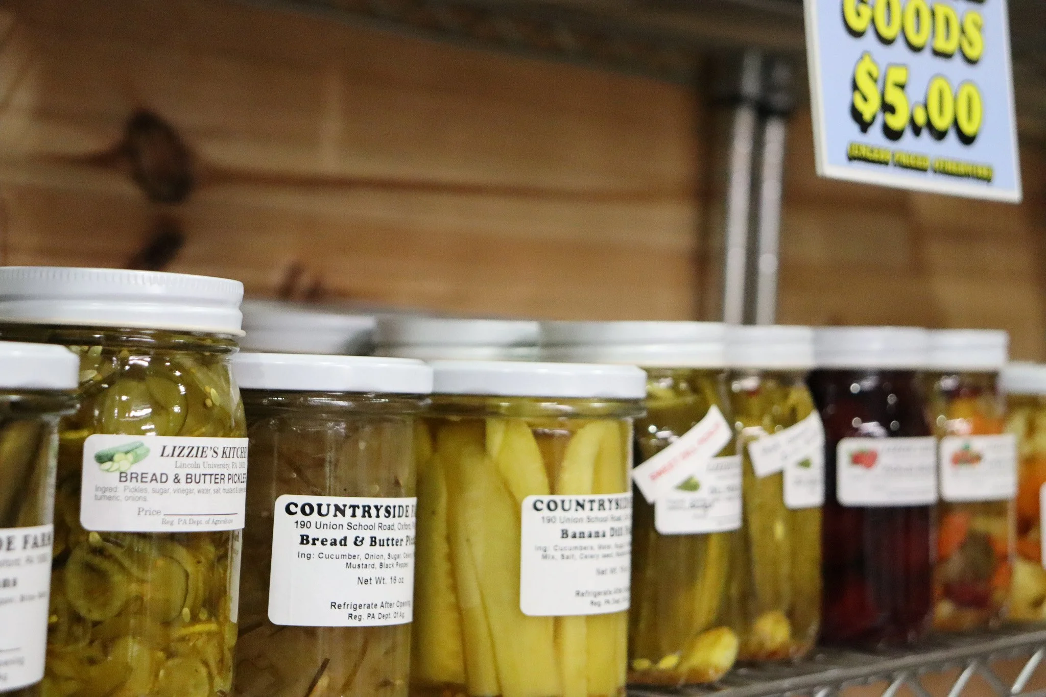 Locally made jarred pickles and preserves arranged on the shelves at Sunny Dreams Farm’s produce stand.