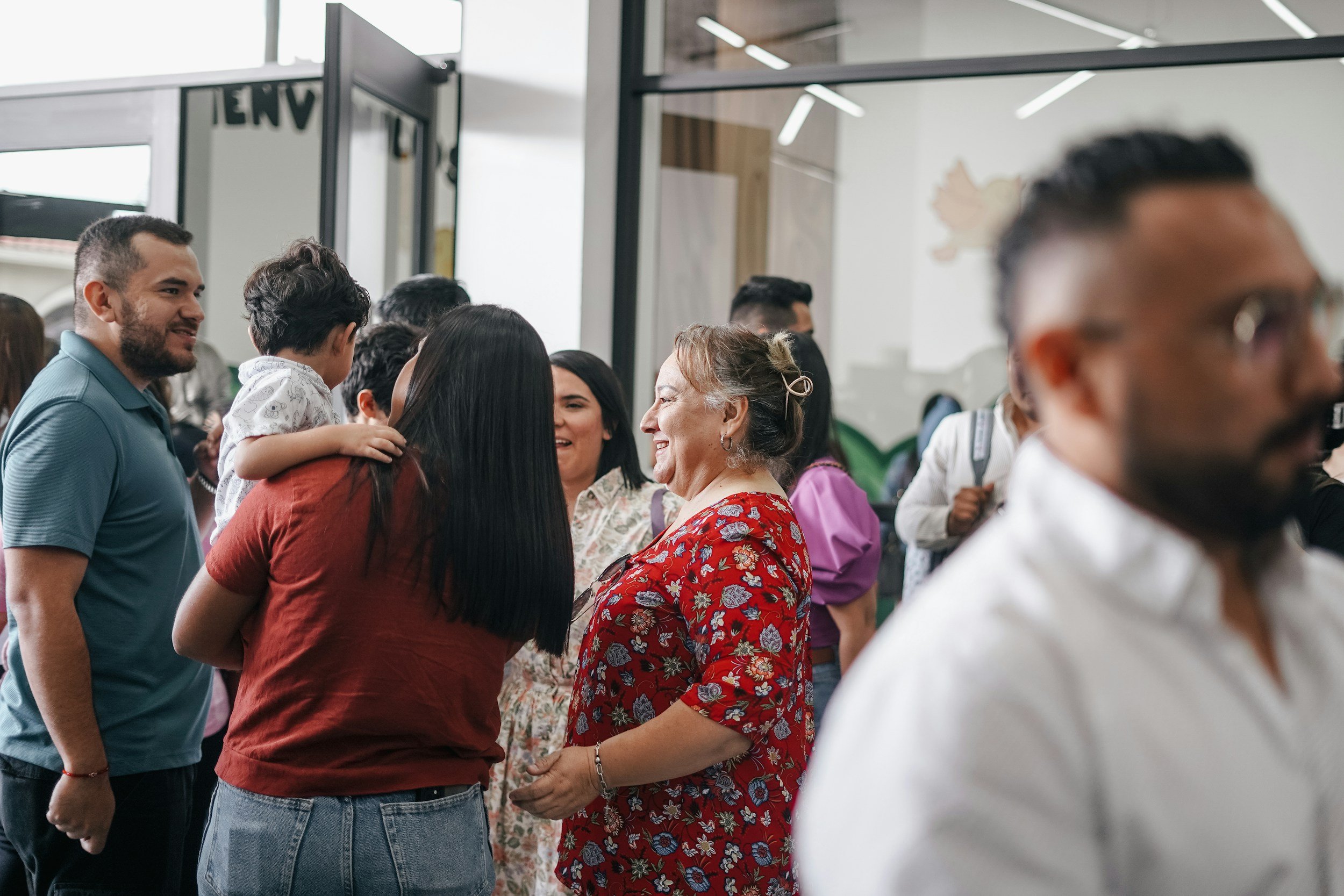 A group of people talking, with a mother holding her child