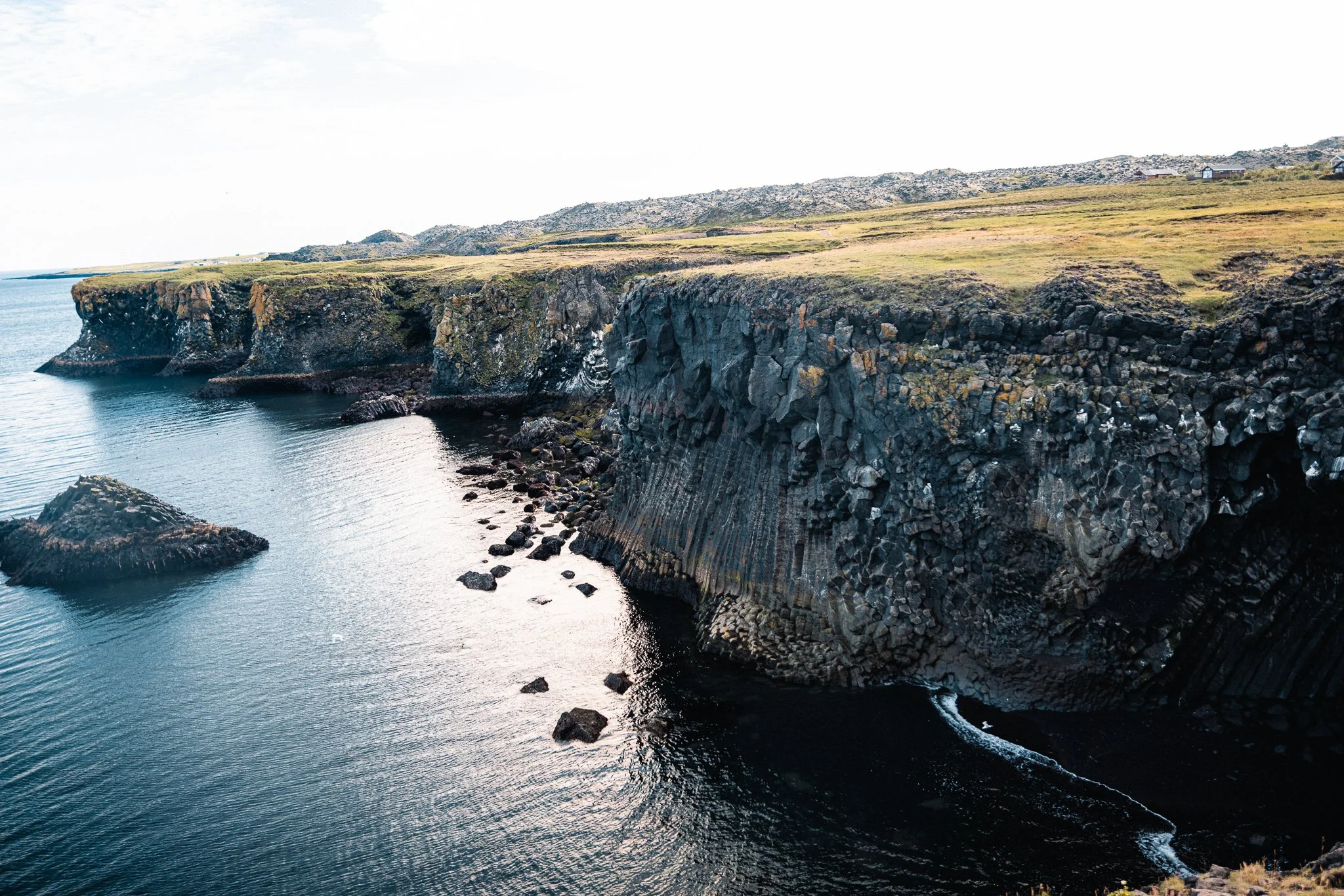 Coastal basalt cliffs with rocky shores and a calm sea.