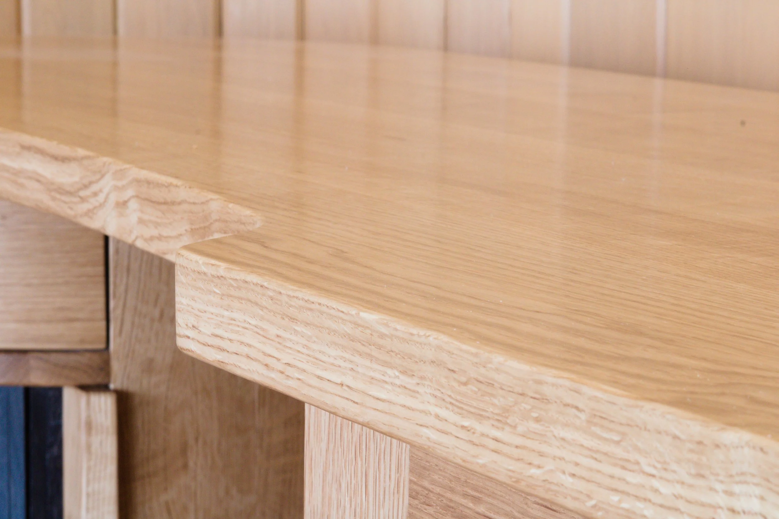 Close-up of a wooden table and bookshelf made from light-colored wood with a smooth finish.