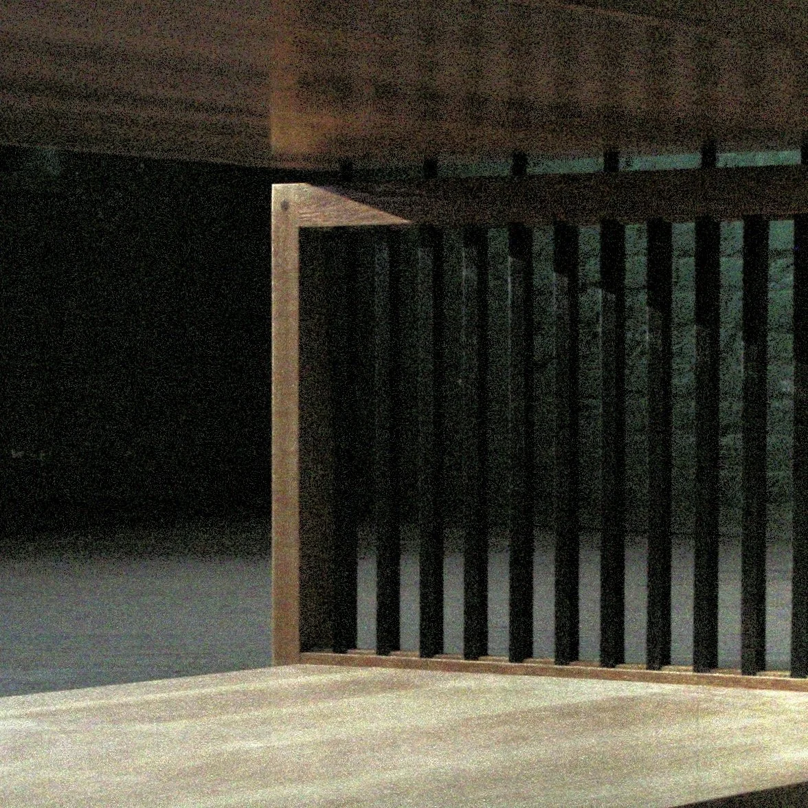 Interior view of a dark staircase with wooden steps and black vertical railing, seen from below.