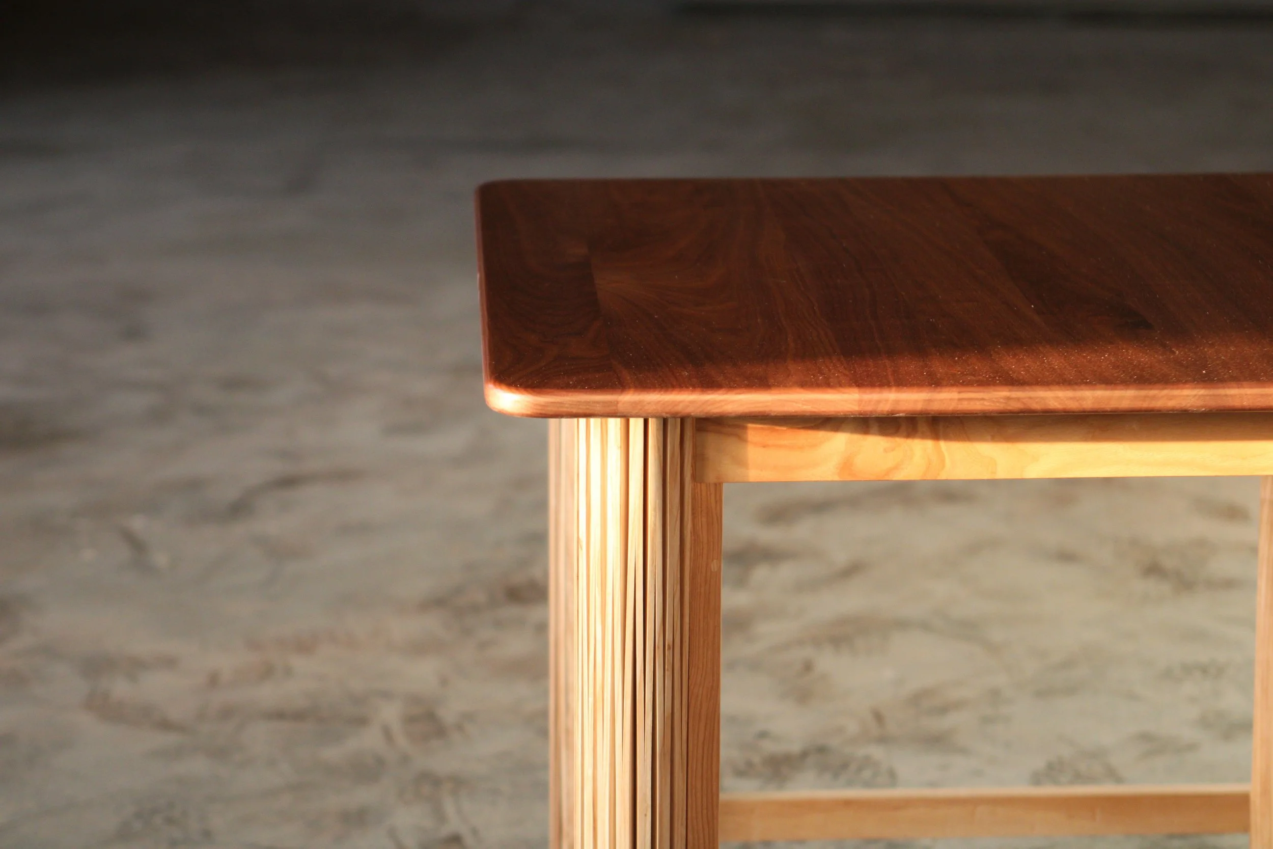 Close-up of a wooden table with a polished dark wood top and light-colored wooden legs.