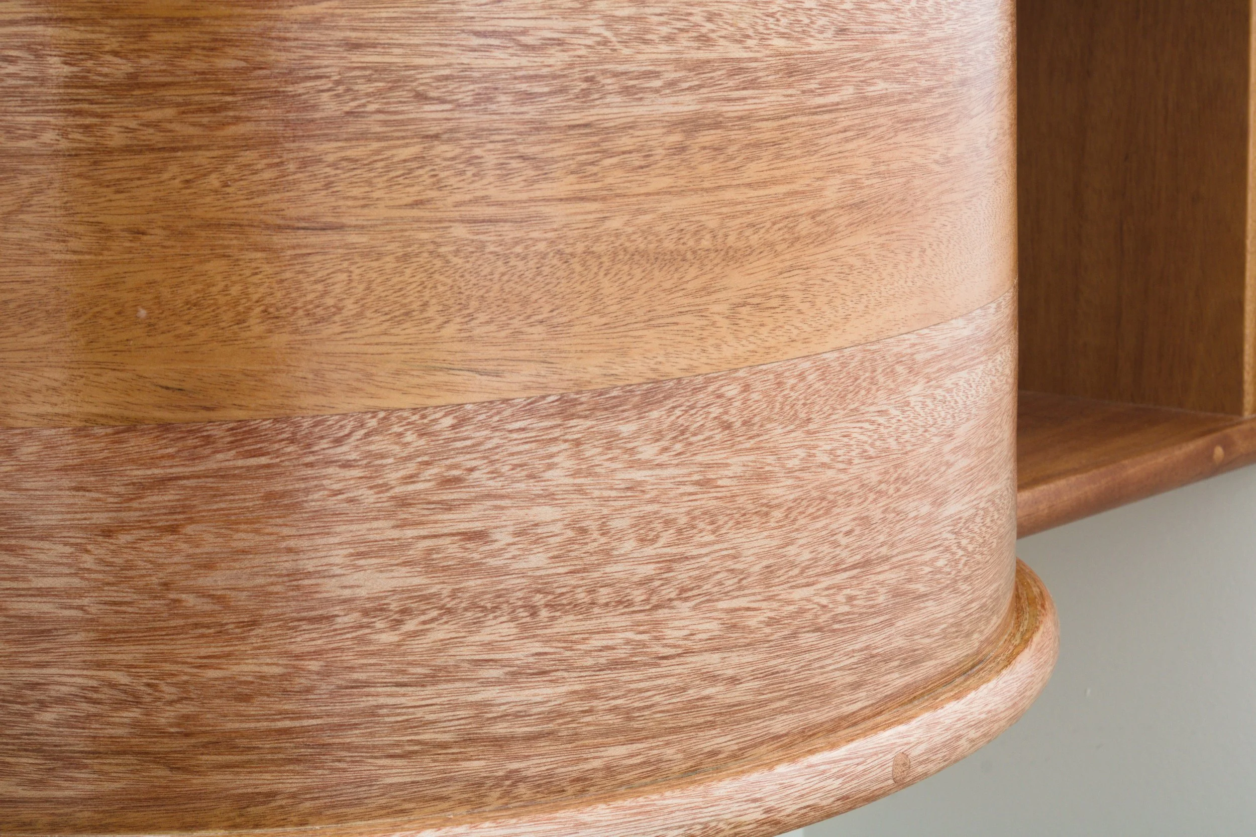 Close-up of a wooden piece of furniture with a rounded edge and visible wood grain.