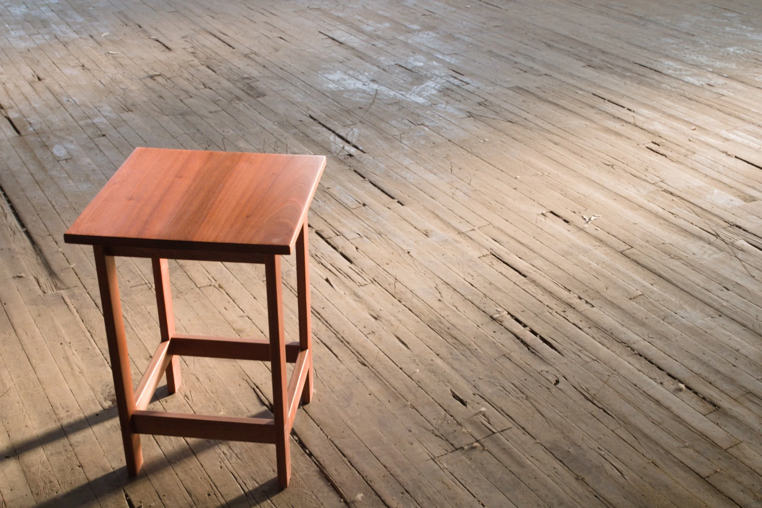 A small wooden chair sits on a worn wooden floor with visible cracks and scratches.