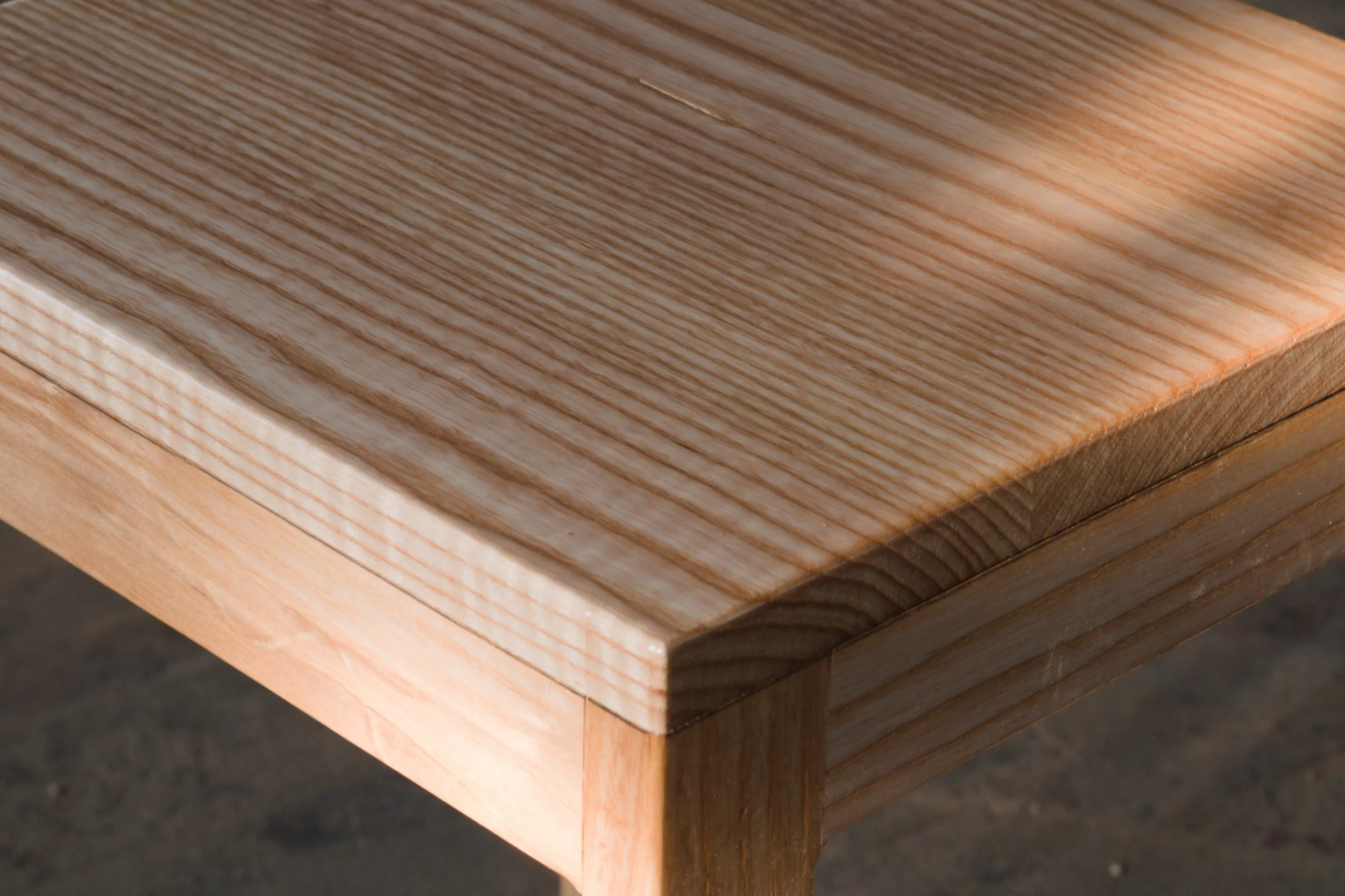 Close-up view of a wooden table corner showing natural wood grain and texture.